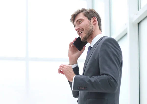 Empresário falando em um telefone celular que está perto da janela do escritório — Fotografia de Stock