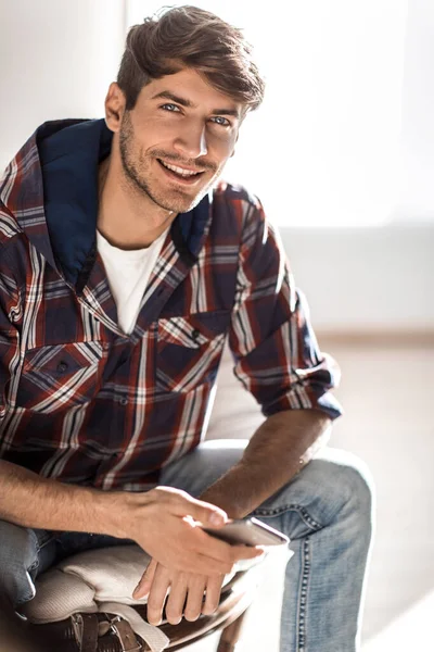 Succès jeune homme avec un téléphone portable assis dans une chaise — Photo