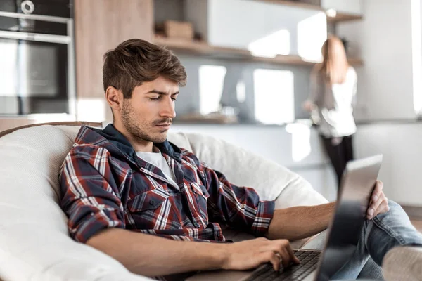 Sidovy. framgångsrik ung man med laptop sitter i stolen — Stockfoto