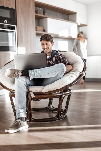 Giovane utilizza un computer portatile nel suo appartamento moderno . — Foto Stock
