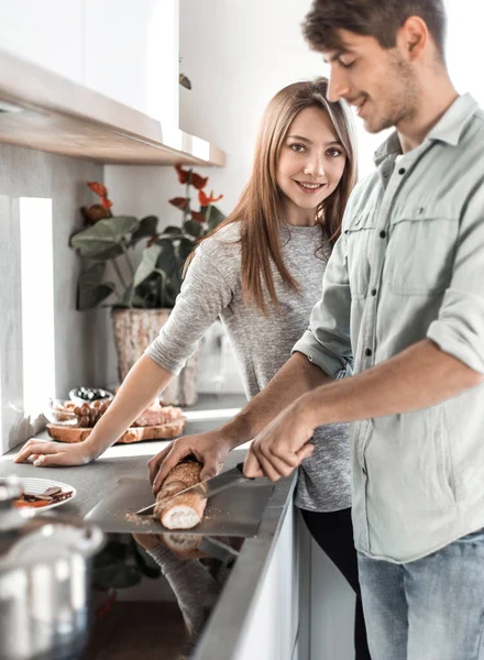 Jovem casal preparando sanduíches em sua cozinha — Fotografia de Stock