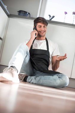 cep telefonu katta oturan konuşan mutlu genç adam