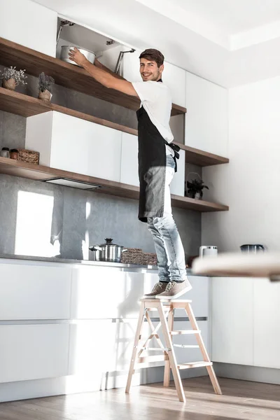 Homem de pé em uma escada na cozinha da casa — Fotografia de Stock