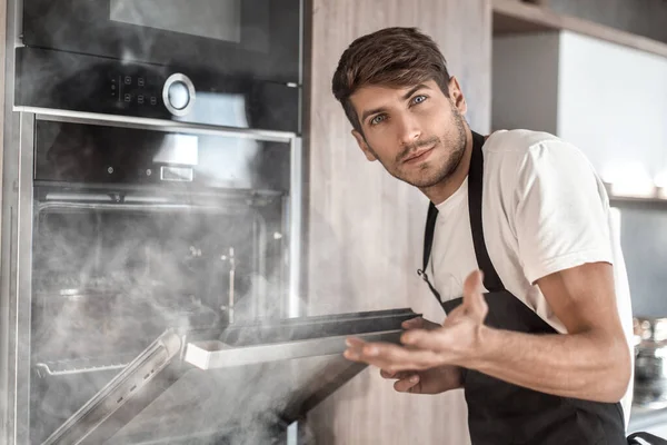 Jovem frustrado de pé perto do forno quebrado — Fotografia de Stock