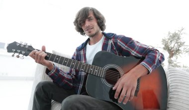 adam bir şarkı söyler ve kanepede oturan gitar çalar.