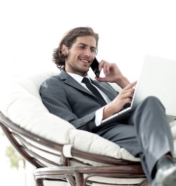 onun evinde sandalyede oturan smartphone cep telefonu ile konuşurken işadamı