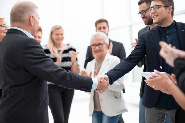 Twee zakenmensen schudden elkaar de hand waar hun collega 's bij zijn — Stockfoto