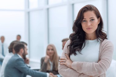 Ofisin arka planında kendine güvenen genç bir iş kadını var..