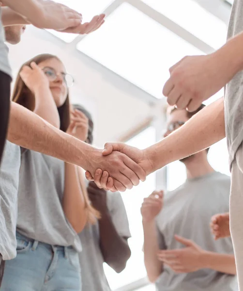 Apretón de manos de los jóvenes en el fondo del equipo de aplausos — Foto de Stock