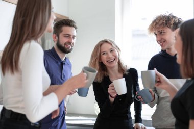 Gülümseyen arkadaşlar çay kupalarıyla buluşuyorlar.