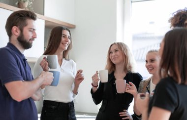 Gülümseyen arkadaşlar çay kupalarıyla buluşuyorlar.