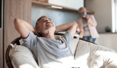 Olgun bir adam rahat bir papazın koltuğunda oturuyor. .