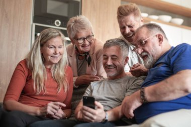 Akıllı telefonlu bir grup eski dost sıcak bir oturma odasında oturuyor..