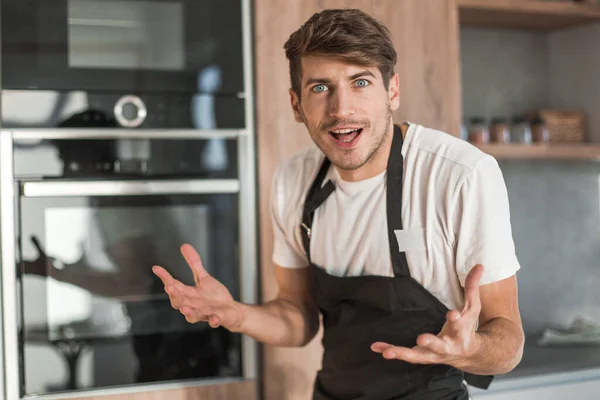 Fiatal férfi áll mellett törött sütő otthon konyha — Stock Fotó