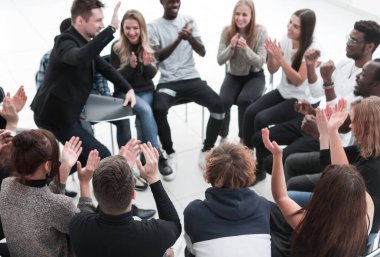 Bir grup seminer katılımcısı bir çemberin içinde otururken alkışlıyor