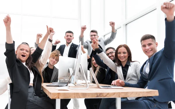 Grote groep diverse medewerkers vieren het terwijl ze aan een tafel zitten — Stockfoto