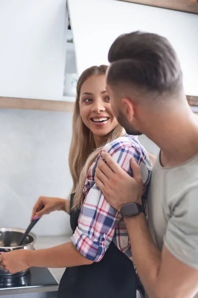 Молодой человек шутит с женой на кухне — стоковое фото