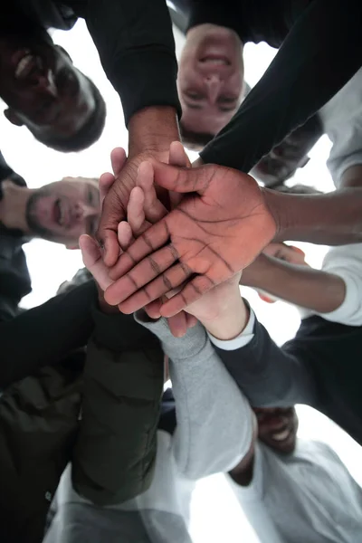 Vista inferior. um grupo de jovens diversos unindo as mãos — Fotografia de Stock