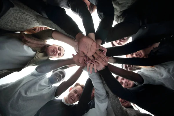 Ansicht von unten. Gruppe glücklicher junger Leute, die einen Stapel Hände machen — Stockfoto