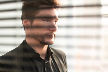 Başarılı çekici genç iş adamı parlak ofiste duruyor.