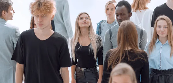 Femme sérieuse debout devant un groupe décontracté de jeunes — Photo