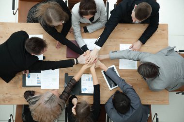 Üst Manzara. İş ekibi masaüstünde el ele tutuşuyor..