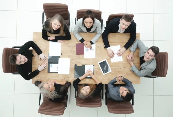 Vista superior. joven equipo de negocios sentado en una mesa y mirando a la cámara — Foto de Stock