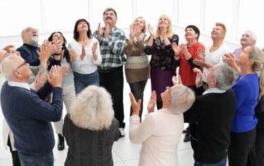 Bir grup yaşlı insan el çırpıyor.