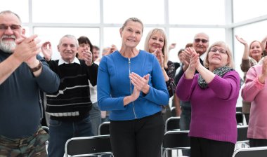 Bir grup yaşlı insan bir çemberin içinde oturmuş alkışlıyorlar.