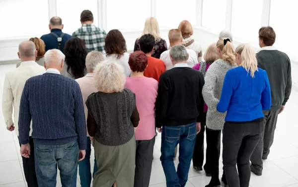 A group of old people standing at their back indoors — стоковое фото