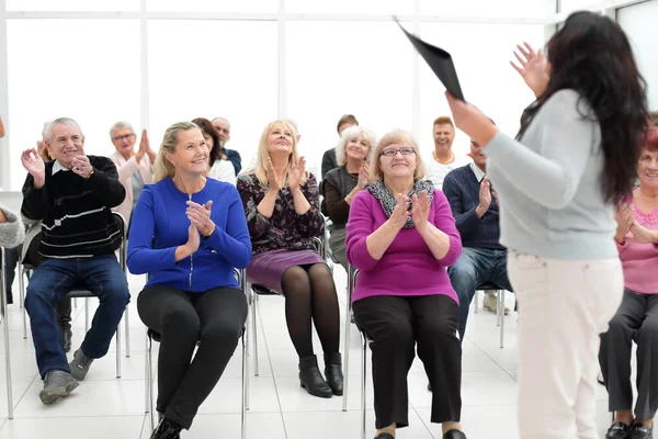 Hocası elinde klasörle yaşlılara iş öğretiyor.
