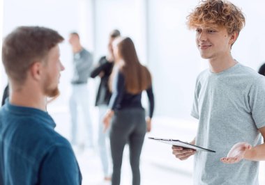 Dijital tabletli genç bir çalışan meslektaşıyla konuşuyor.