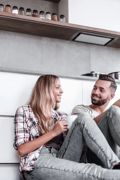 年轻夫妇坐在厨房地板上喝咖啡 — 图库照片