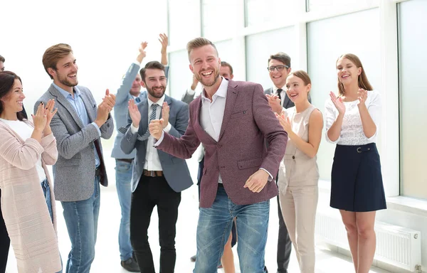 Jungunternehmer vor dem Hintergrund applaudierender Geschäftsleute. — Stockfoto