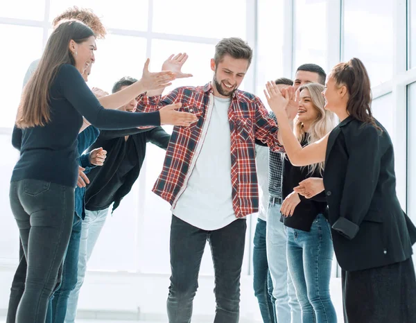 Bir grup mutlu çalışan meslektaşlarını tebrik ediyor.