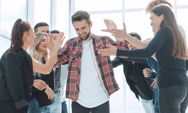 Bir grup mutlu çalışan meslektaşlarını tebrik ediyor.