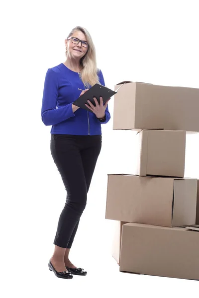 Donna sorridente con un blocco a molla per firmare mentre in piedi vicino a scatole di cartone — Foto Stock