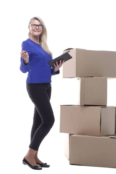 Donna sorridente con un blocco a molla per firmare mentre in piedi vicino a scatole di cartone — Foto Stock