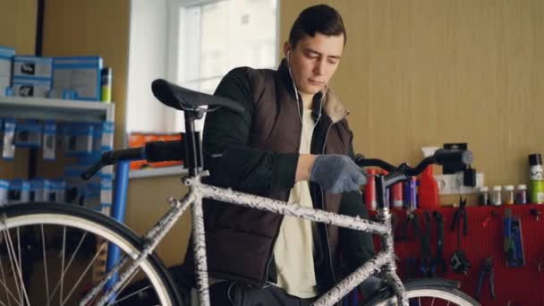 Professionell serviceman är fastställande cykel handtag-bar vrida allen nyckel för att dra åt gemensamma och lyssnar på musik med hörlurar. Speciella verktyg, reservdelar och utrustning är synliga. — Stockvideo