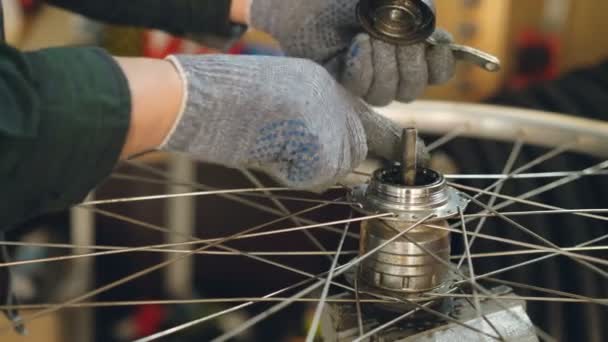 Close-up shot van man hand in beschermende handschoen mechanisme van fietswiel tijdens het controleren en herstellen van de kapotte fiets monteren. Mensen, werk en beroep concept. — Stockvideo