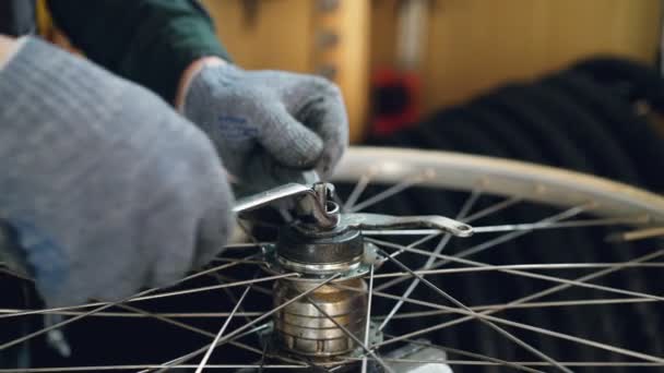 Close-up tiro da mão masculina em luva gordurosa apertando parafuso no mecanismo de roda de bicicleta usando chave de instrumento profissional. Conceito de trabalho, pessoas e profissão . — Vídeo de Stock