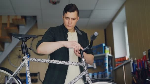 Forte homem bonito hábil mecânico está concentrado em reparar guidão de bicicleta quebrada em sua pequena oficina. Pessoas qualificadas e conceito de manutenção . — Vídeo de Stock