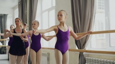 Ciddi kızlar kol hareketleri Studio bale dersi sırasında pratik. Öğretmen profesyonel balerin pozisyon düzeltme ve talimatlar vermek yardım ediyor.