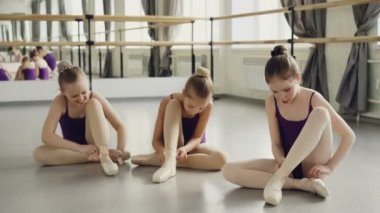 İnce güzel çocuk studio katta bale terlik giyen ve konuşuyor. Büyük ayna, bale barre, parlak bodysuits ve güzel iç görülebilir.
