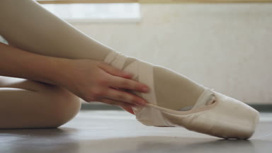 Pointe Ayakkabı ve elleri üzerinde profesyonel Ayakkabı koyarak ve bacak çevresinde Şerit ipe yakın çekim çekim küçük kız ayak. Bale ayakkabıları, dans ve kıyafetleri kavramı.