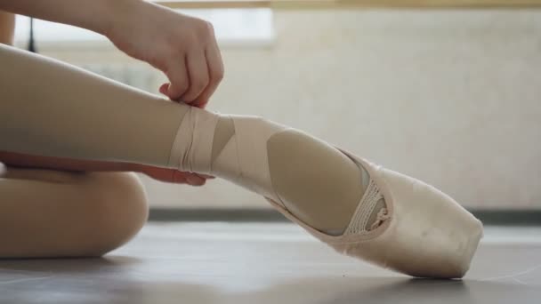 Primer plano del pie de las niñas en zapato puntiagudo y las manos poniéndose calzado profesional y atando cinta alrededor de la pierna. Ballet-shoes, concepto de danza y atuendo . — Vídeo de stock