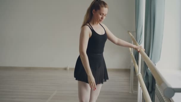 Cheeful 成年女子专业芭蕾舞演员在芭蕾舞酒吧 stading 踮起脚尖, 抬腿, 做旋转。人, 艺术和舞蹈概念. — 图库视频影像