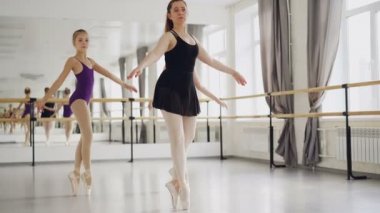 İki kız bale dansçıları Studio bale dersi sırasında deneyimli öğretmenleri ile uçlarında dans pratik. Büyük ayna, bale barre ve windows tarafından görülebilir.