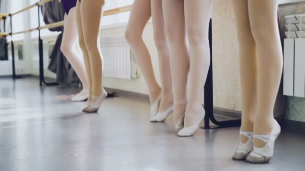 Slow motion of slim womens legs in pointe shoes standing on tiptoes moving gracefully and stretching during ballet class. Body, choreography, art concept.