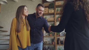 Evli çift daire satın alma, kadın emlakçı elini sıkarken o zaman sarılma, Öpüşme ve gülüyor. Yer değiştirme, mutluluk ve konaklama konsepti.